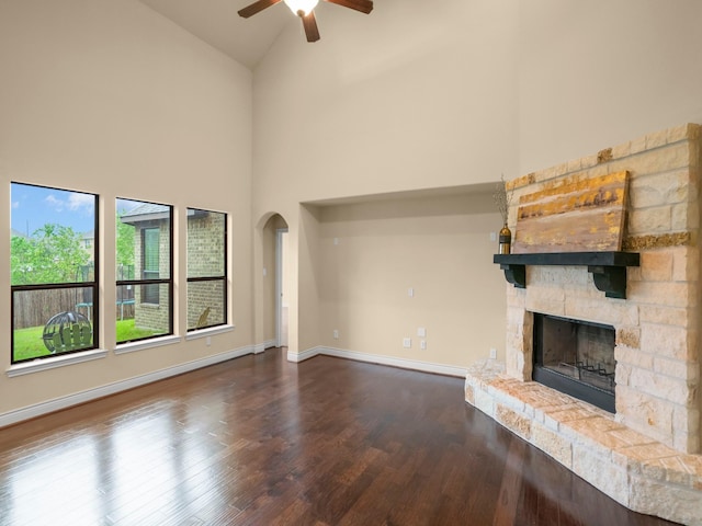 12530 Sharps Ln, Magnolia, TX 77354 - unfurnished living room featuring high vaulted ceiling, ceiling fan, a stone fireplace, dark wood finished floors, and arched walkways