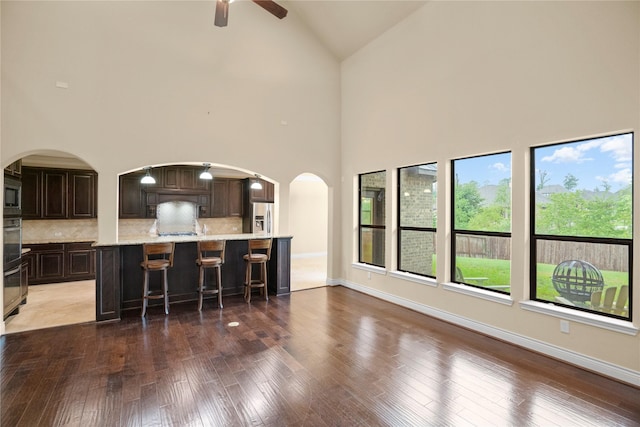 12530 Sharps Ln, Magnolia, TX 77354 - living room with ceiling fan, high vaulted ceiling, arched walkways, wood-type flooring, and baseboards