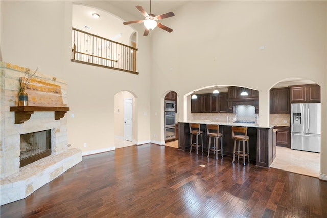 12530 Sharps Ln, Magnolia, TX 77354 - living area with a ceiling fan, hardwood / wood-style floors, a towering ceiling, a stone fireplace, and arched walkways