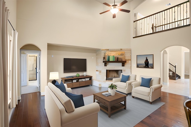 12530 Sharps Ln, Magnolia, TX 77354 - living room with a towering ceiling, arched walkways, a ceiling fan, dark wood finished floors, and a fireplace