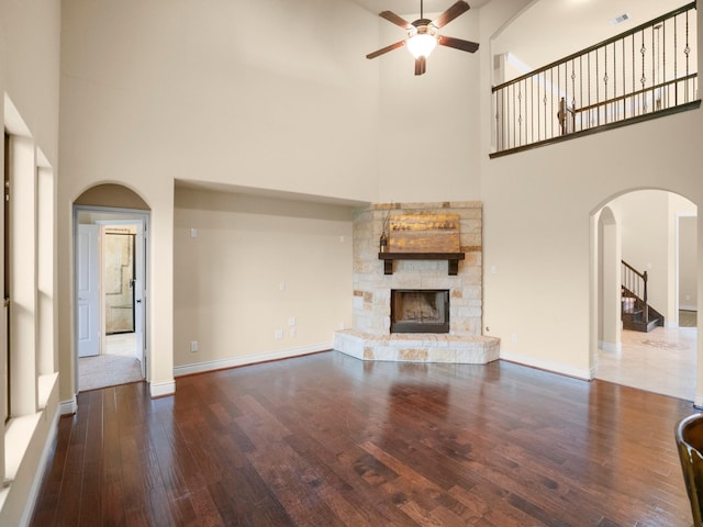 12530 Sharps Ln, Magnolia, TX 77354 - unfurnished living room with a towering ceiling, ceiling fan, wood finished floors, arched walkways, and a fireplace