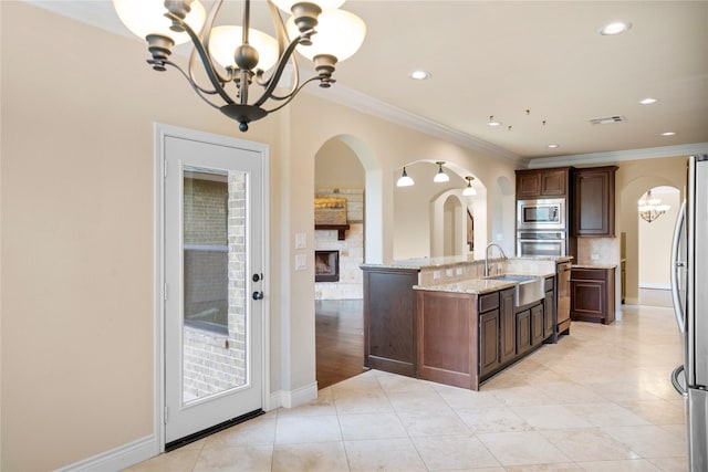 12530 Sharps Ln, Magnolia, TX 77354 - kitchen with a chandelier, appliances with stainless steel finishes, a sink, a fireplace, and arched walkways