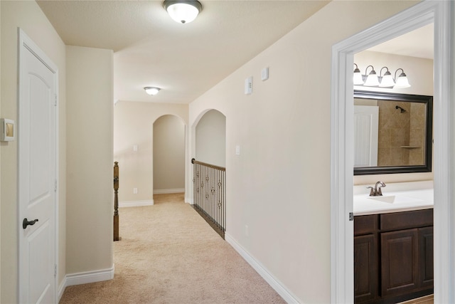 12530 Sharps Ln, Magnolia, TX 77354 - hallway featuring light carpet, a sink, and baseboards
