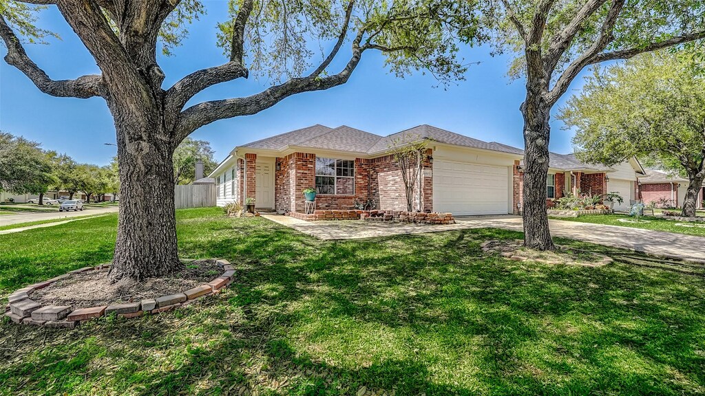 single story home with brick siding, a garage, concrete driveway, and a front yard