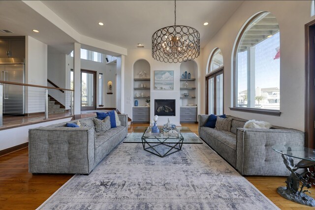 4206 Turks Pt, Galveston, TX 77554 - living room with built in features, wood finished floors, recessed lighting, an inviting chandelier, and stairs