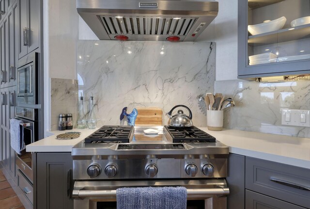 4206 Turks Pt, Galveston, TX 77554 - kitchen with gray cabinets, backsplash, ventilation hood, appliances with stainless steel finishes, and light countertops