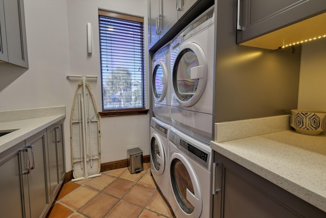 4206 Turks Pt, Galveston, TX 77554 - laundry room featuring light tile patterned floors, stacked washer / dryer, cabinet space, and baseboards