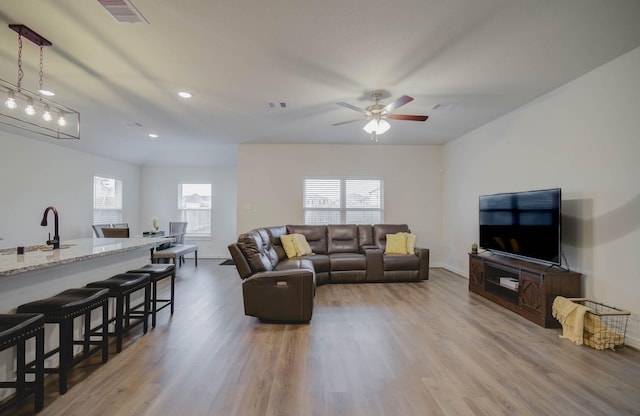 living room featuring ceiling fan, visible vents, and wood finished floors