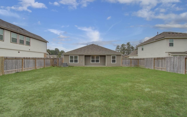 back of house featuring a fenced backyard, central AC, a yard, and a shingled roof