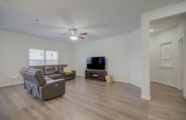 living area with light wood-type flooring, visible vents, baseboards, and ceiling fan