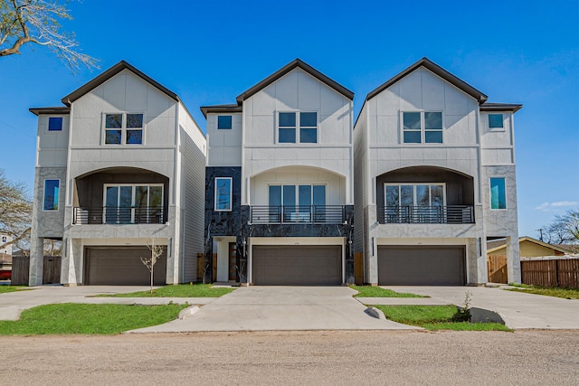 multi unit property with a garage, fence, a balcony, stone siding, and driveway
