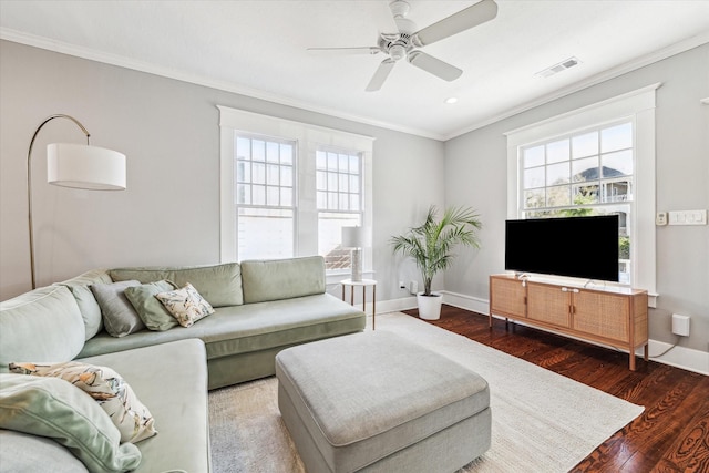 living room featuring visible vents, plenty of natural light, ornamental molding, and wood finished floors