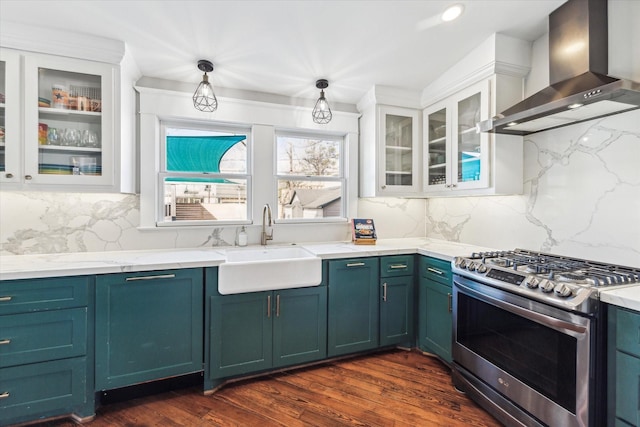 kitchen with dark wood-type flooring, a sink, white cabinetry, wall chimney range hood, and stainless steel range with gas stovetop