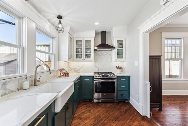 kitchen with stainless steel gas range oven, light stone counters, a healthy amount of sunlight, and wall chimney exhaust hood