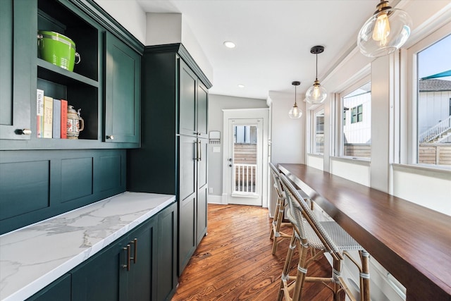 kitchen with green cabinets, light stone countertops, decorative light fixtures, light wood-style floors, and open shelves