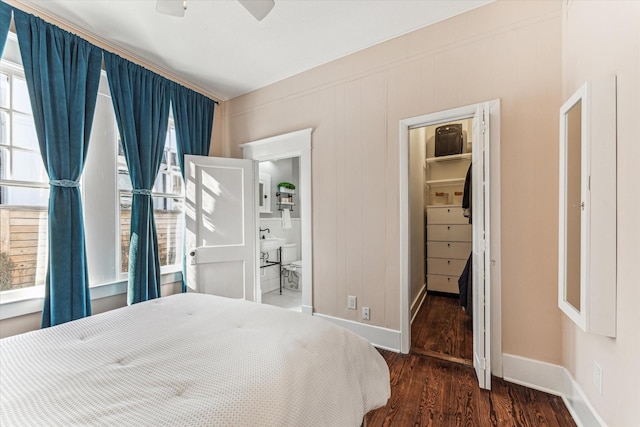 bedroom with baseboards, multiple windows, wood finished floors, and a spacious closet