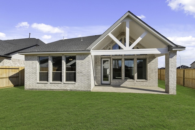 rear view of house with a fenced backyard, brick siding, a patio, and a lawn