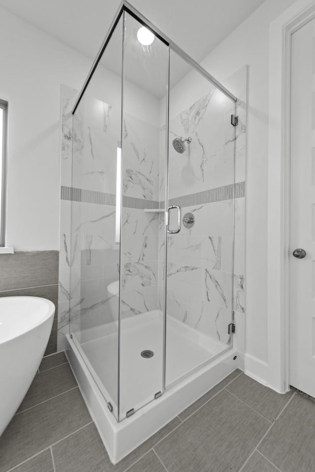 full bathroom with a freestanding bath and a marble finish shower