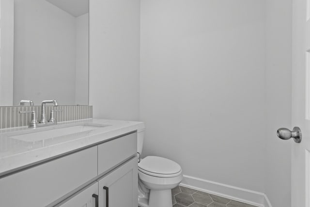 half bath with baseboards, toilet, tile patterned floors, and vanity