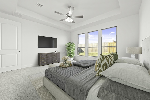 carpeted bedroom with a tray ceiling, baseboards, and visible vents