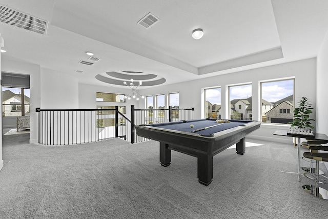 recreation room with carpet floors, a tray ceiling, a chandelier, and visible vents