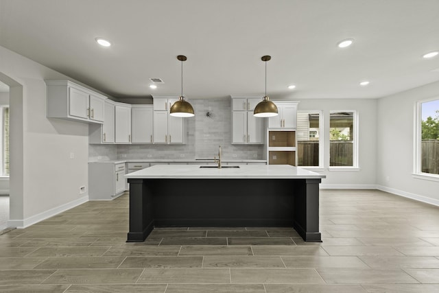 8407 Sheffields Leader, Fulshear, TX 77441 - kitchen with a kitchen island with sink, tasteful backsplash, wood tiled floors, light countertops, and recessed lighting