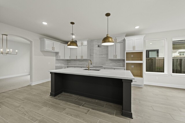 8407 Sheffields Leader, Fulshear, TX 77441 - kitchen featuring light wood-style flooring, a kitchen island with sink, tasteful backsplash, recessed lighting, and white cabinetry