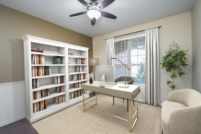 office featuring a wainscoted wall, wood finished floors, and a ceiling fan