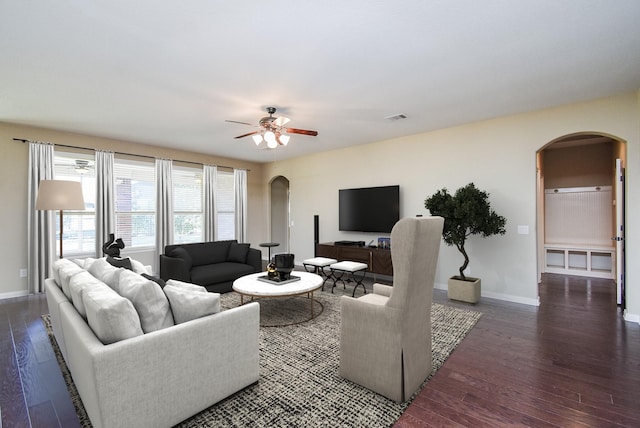 living area with visible vents, a ceiling fan, hardwood / wood-style flooring, arched walkways, and baseboards