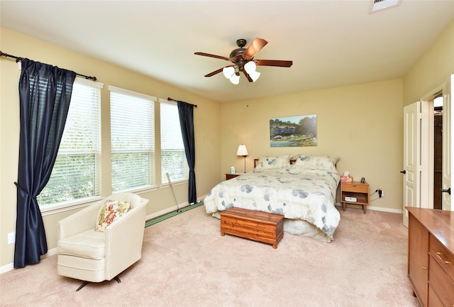 bedroom featuring a ceiling fan, visible vents, light colored carpet, and baseboards