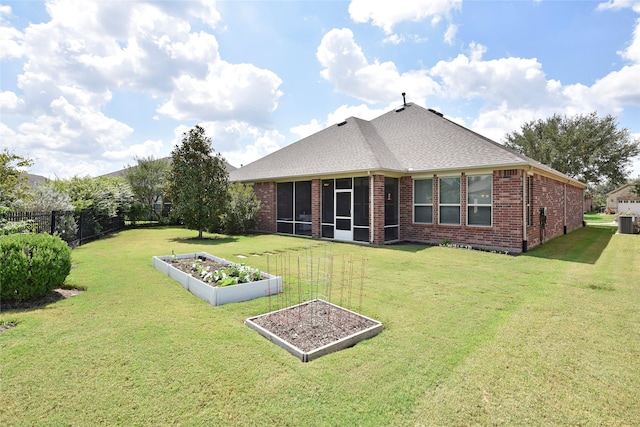 rear view of property with a garden, fence, brick siding, and a lawn