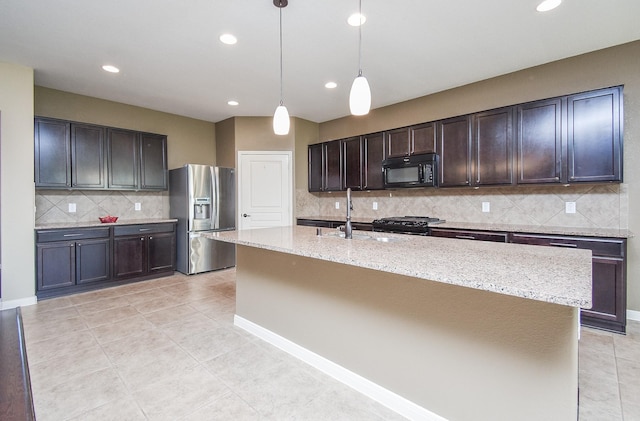 kitchen with a sink, stove, dark brown cabinets, black microwave, and stainless steel fridge