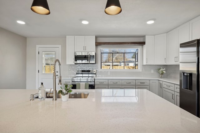 kitchen with a wealth of natural light, stainless steel appliances, tasteful backsplash, and a sink