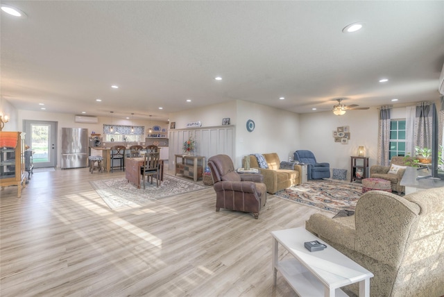 living room with recessed lighting, a wall mounted air conditioner, light wood-style floors, and a ceiling fan