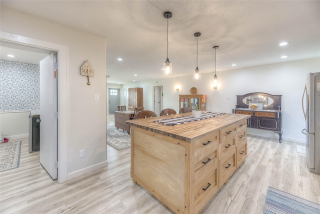 kitchen featuring light brown cabinets, light wood finished floors, recessed lighting, freestanding refrigerator, and butcher block counters