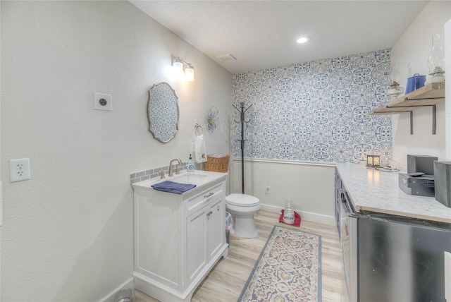 bathroom featuring baseboards, toilet, recessed lighting, wood finished floors, and vanity