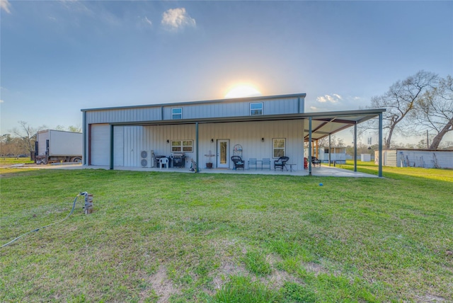 back of house featuring a lawn, a patio, and a garage