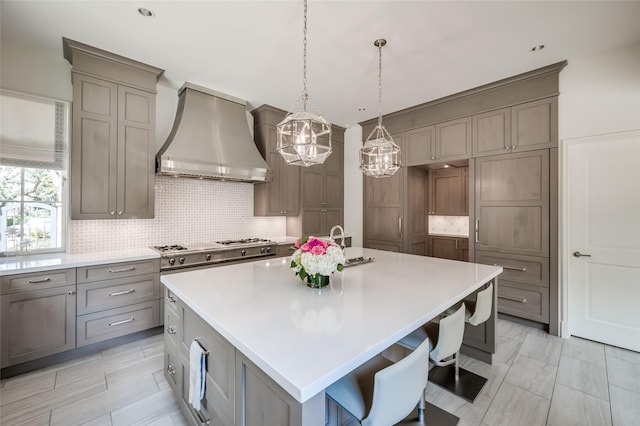 2131 Brentwood Dr, Houston, TX 77019 - kitchen featuring wall chimney exhaust hood, a chandelier, gray cabinetry, and backsplash