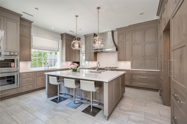 2131 Brentwood Dr, Houston, TX 77019 - kitchen with wall chimney range hood, a kitchen bar, backsplash, a kitchen island with sink, and recessed lighting