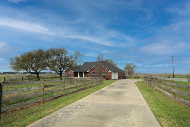 view of front of home featuring fence, a rural view, and concrete driveway