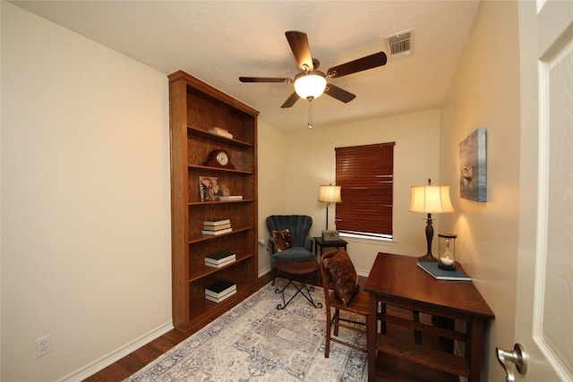 office with baseboards, visible vents, a ceiling fan, and wood finished floors