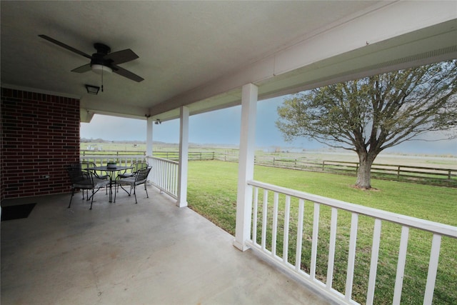 view of patio / terrace with outdoor dining space, ceiling fan, a rural view, and fence