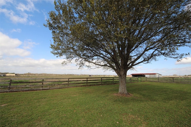 view of yard with fence and a rural view