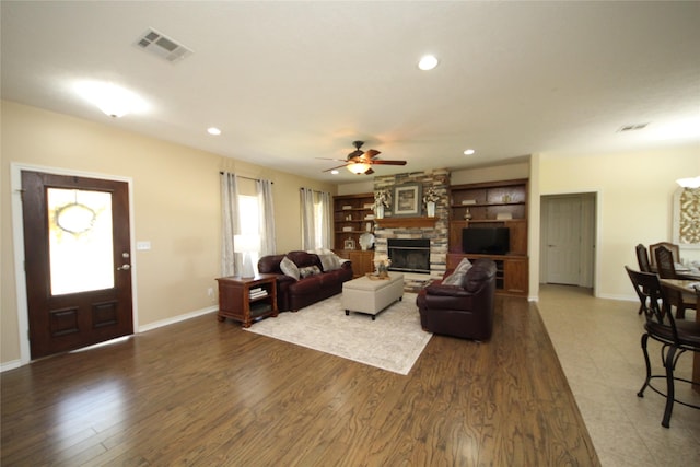 living room with visible vents, recessed lighting, a ceiling fan, a stone fireplace, and dark wood finished floors
