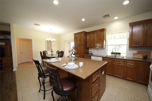 kitchen featuring a breakfast bar, visible vents, a sink, and an inviting chandelier