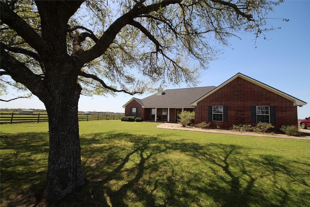 single story home with brick siding, fence, and a front lawn