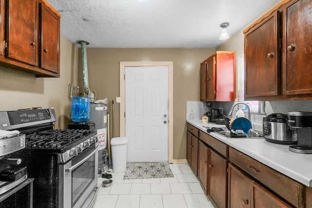 2105 Russell St, Houston, TX 77026 - kitchen with light countertops, water heater, stainless steel gas stove, a textured ceiling, and a sink