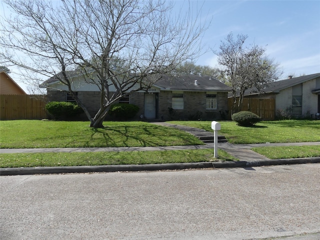 view of front of house featuring brick siding, a front lawn, and fence