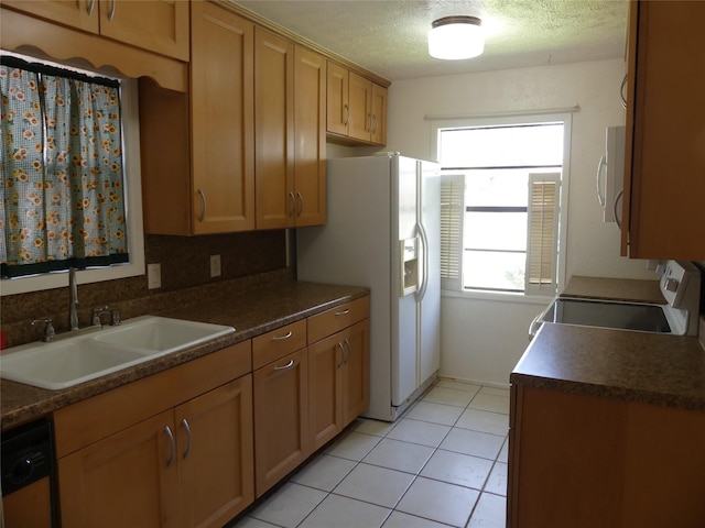 kitchen featuring white appliances, light tile patterned floors, a sink, a textured ceiling, and dark countertops