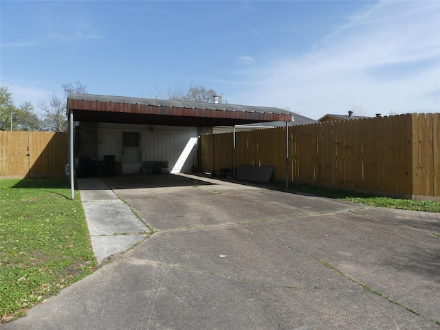 view of parking / parking lot featuring concrete driveway and fence